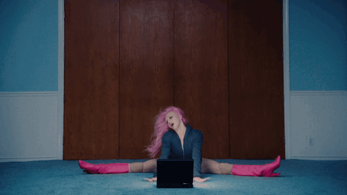 a woman with pink hair and blue shorts is laying on the floor