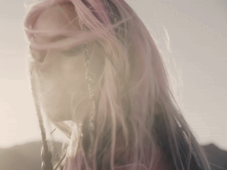A Woman With Pink Hair And Braids Looks Down GIF