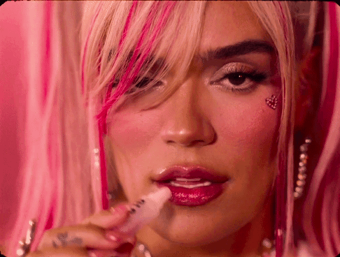 A Woman With Pink Hair Is Applying Lip Gloss GIF
