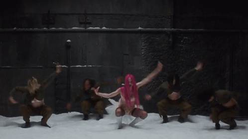 a woman with pink hair is dancing in front of a group of dancers