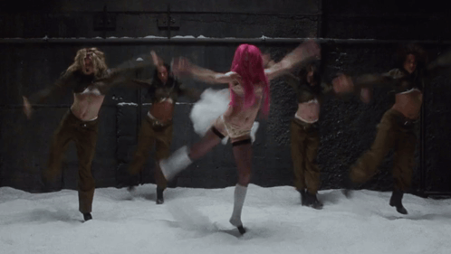 a woman with pink hair is dancing in the snow with other women