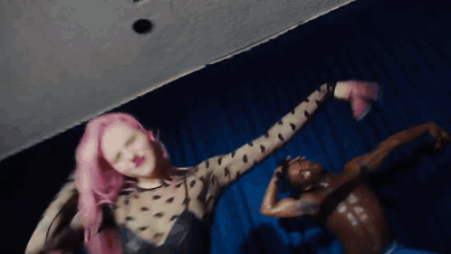 a woman with pink hair is dancing next to a man with no shirt on