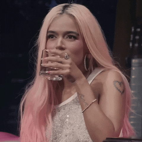 A Woman With Pink Hair Is Drinking From A Clear Glass GIF