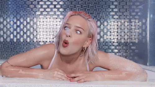 A Woman With Pink Hair Is In A Bathtub GIF