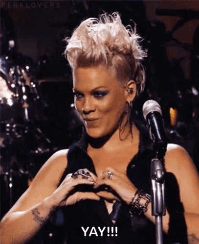 A Woman With Pink Hair Is Making A Heart Shape With Her Hands And Says Yay GIF