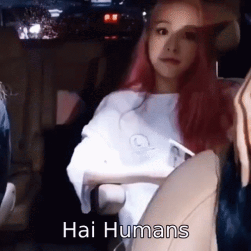 A Woman With Pink Hair Is Sitting In A Car With The Words Hai Humans Written On The Bottom . GIF