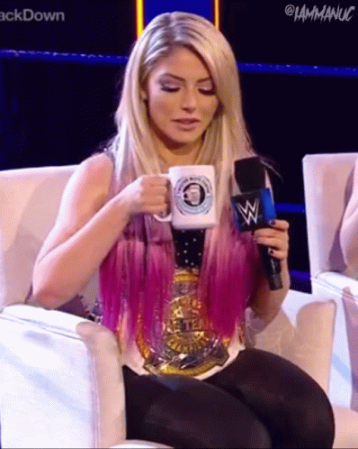 A Woman With Pink Hair Is Sitting In A Chair Holding A Microphone And A Mug . GIF