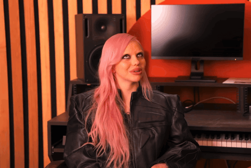 a woman with pink hair is sitting in front of a computer