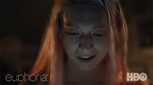 A Woman With Pink Hair Is Smiling While Looking At Her Phone With Euphoria Hbo Written On The Bottom GIF
