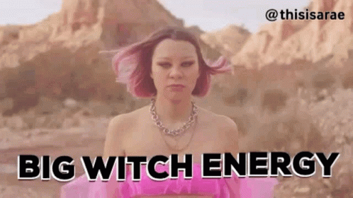 A Woman With Pink Hair Is Standing In The Desert With The Words `` Big Witch Energy '' . GIF