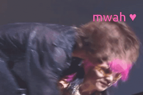 A Woman With Pink Hair Is Standing Next To A Man Without A Shirt And The Word Mwah Is Above Them GIF