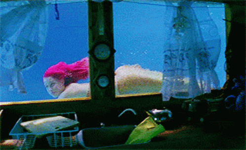 a woman with pink hair is swimming underwater in a tank