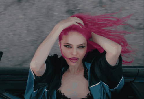 a woman with pink hair is wearing a blue jacket and black bra