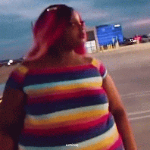 A Woman With Pink Hair Is Wearing A Colorful Striped Dress GIF
