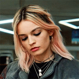 A Woman With Pink Hair Is Wearing Hoop Earrings And A Choker Necklace GIF