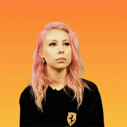 A Woman With Pink Hair Wears A Black Shirt With A Ferrari Logo On It GIF