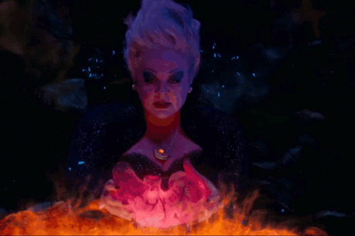 A Woman With Purple Hair And A Necklace With A Red Stone GIF