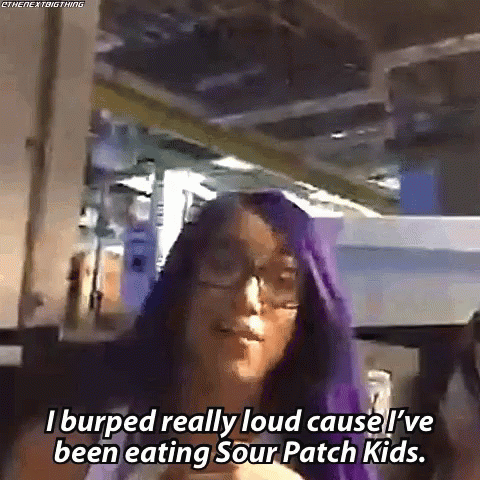 A Woman With Purple Hair And Glasses Is Talking About Sour Patch Kids GIF