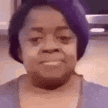 A Woman With Purple Hair Is Smiling And Wearing A Purple Shirt . GIF