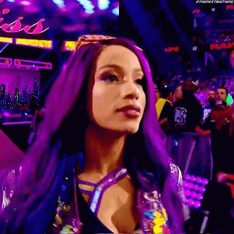 A Woman With Purple Hair Is Standing In Front Of A Crowd In A Stadium . GIF