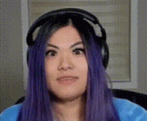 A Woman With Purple Hair Is Wearing Headphones And Making A Face . GIF