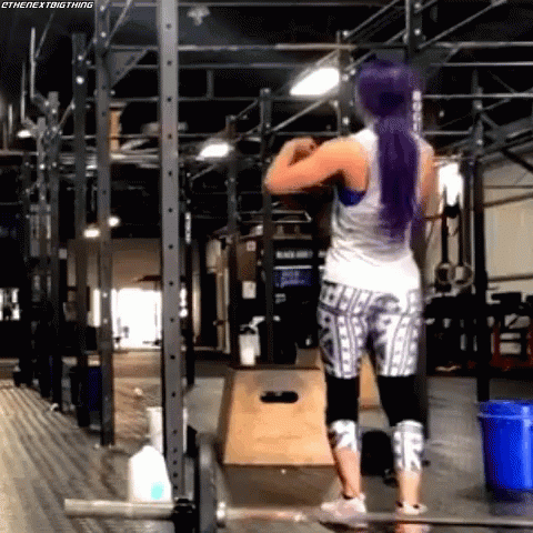 A Woman With Purple Hair Is Working Out In A Gym . GIF