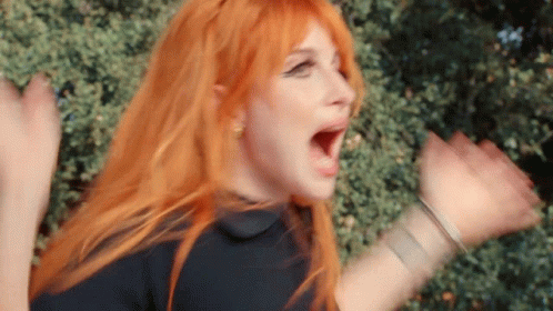 A Woman With Red Hair And A Black Shirt Is Screaming With Her Mouth Open . GIF