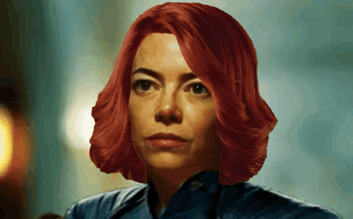 a woman with red hair and a blue shirt is looking at the camera