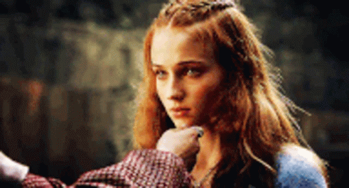 A Woman With Red Hair And A Crown On Her Head Is Being Touched By A Man 'S Hand . GIF