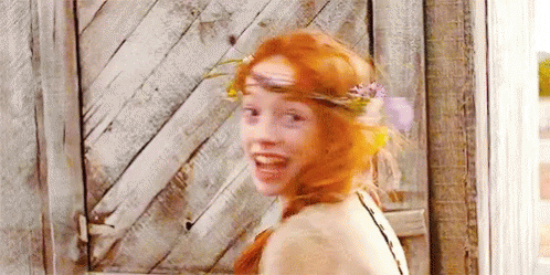 A Woman With Red Hair And A Flower Crown On Her Head Is Smiling . GIF