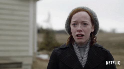 A Woman With Red Hair And A Hat Stands In Front Of A Netflix Sign GIF