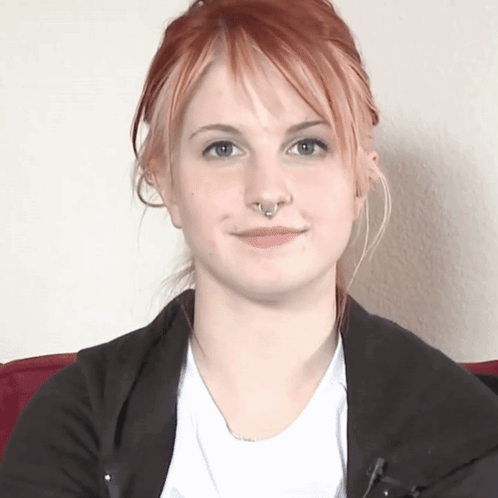 A Woman With Red Hair And A Nose Ring Looks At The Camera GIF