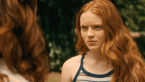 A Woman With Red Hair And A Striped Tank Top GIF