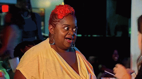 A Woman With Red Hair And A Yellow Shirt Is Making A Funny Face GIF
