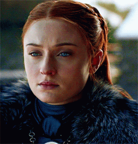 A Woman With Red Hair And Blue Eyes Is Wearing A Black Fur Coat GIF