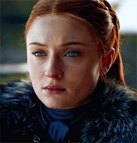 A Woman With Red Hair And Blue Eyes Is Wearing A Black Fur Coat GIF