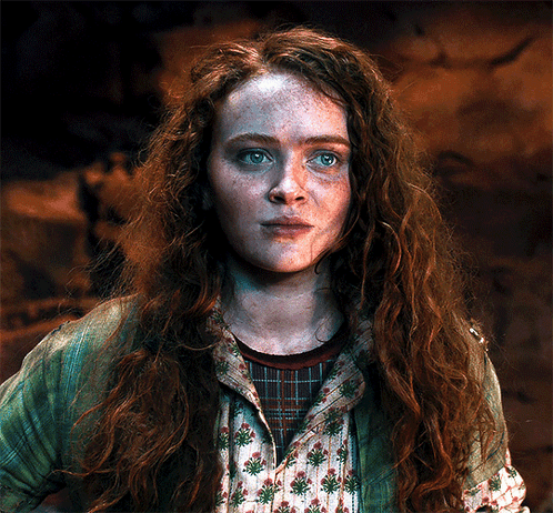 A Woman With Red Hair And Freckles Is Wearing A Green Jacket And A Plaid Shirt GIF