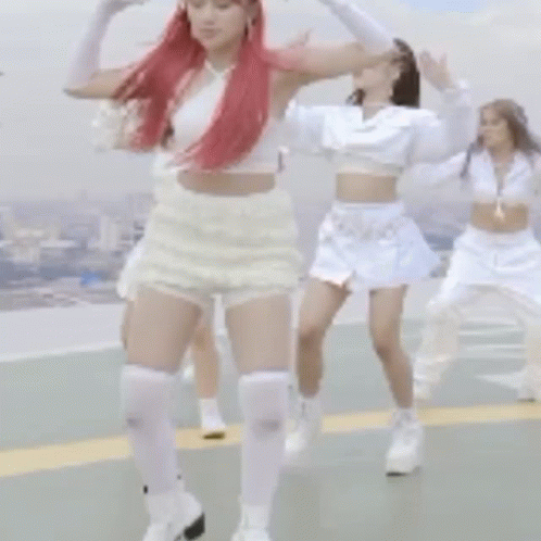 a woman with red hair and white shorts is dancing with other women