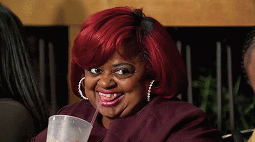 A Woman With Red Hair Drinking From A Plastic Cup With A Straw GIF