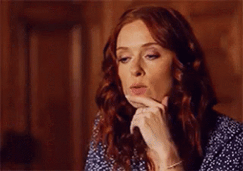 A Woman With Red Hair Is Blowing A Kiss While Holding Her Hand To Her Face . GIF