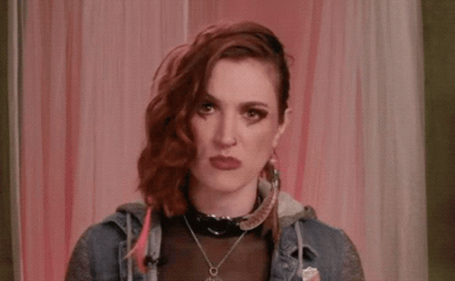 A Woman With Red Hair Is Covering Her Face With Her Hand While Talking On A Phone . GIF