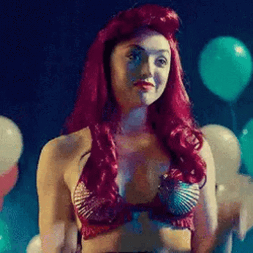 A Woman With Red Hair Is Dressed As A Mermaid In A Bikini Top . GIF