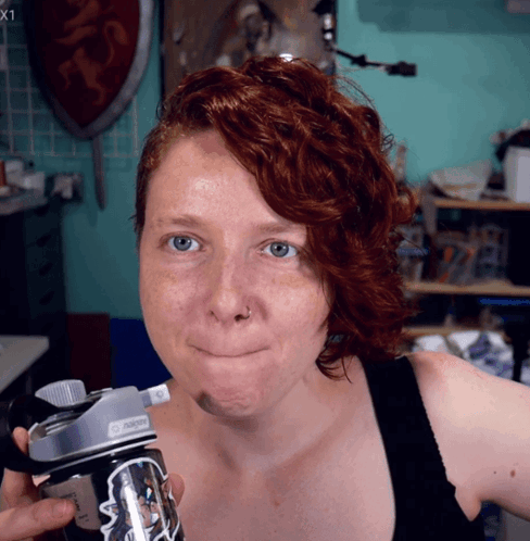 A Woman With Red Hair Is Holding A Nalgene Bottle GIF