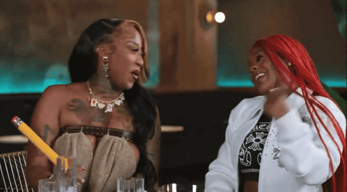 A Woman With Red Hair Is Holding A Pencil While Talking To Another Woman GIF