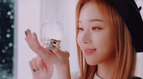 A Woman With Red Hair Is Holding A Snow Globe In Her Hand GIF