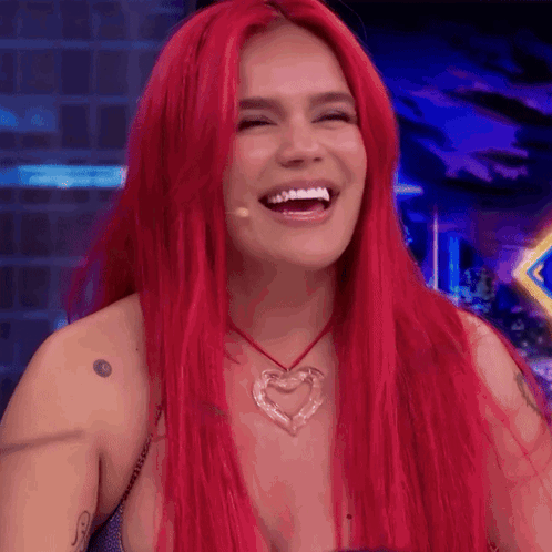 A Woman With Red Hair Is Laughing And Wearing A Heart Shaped Necklace GIF
