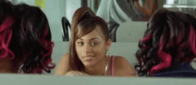 A Woman With Red Hair Is Looking At Herself In A Mirror In A Salon . GIF