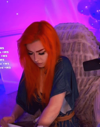 a woman with red hair is sitting in a chair with purple lights behind her .