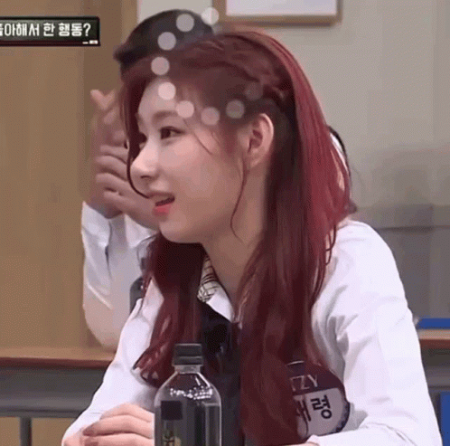 A Woman With Red Hair Is Sitting In A Classroom With A Bottle Of Water . GIF