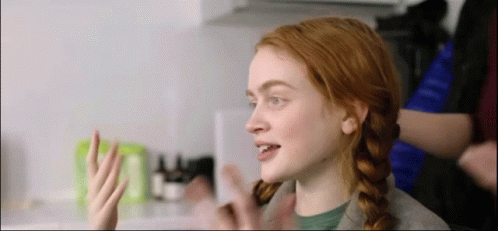 A Woman With Red Hair Is Sitting In A Kitchen With Her Hair In Pigtails . GIF